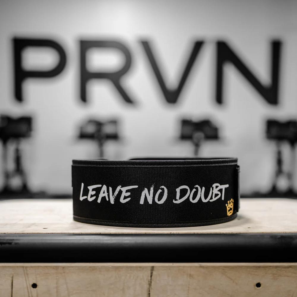 2POOD PRVN Belt – schwarzer Gewichthebergürtel mit weißem „LEAVE NO DOUBT“-Schriftzug und goldener Krone, aufgenommen vor PRVN-Logo im Gym.